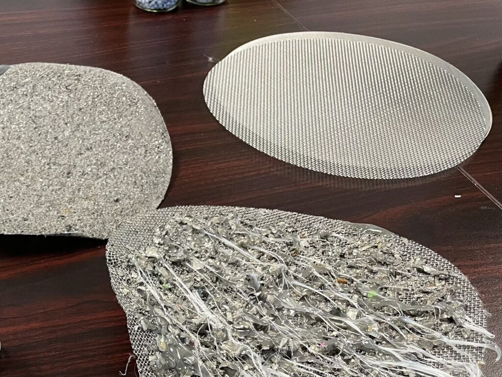 Three metal filters, two used, showing the amount of debris removed from plastic during recycling