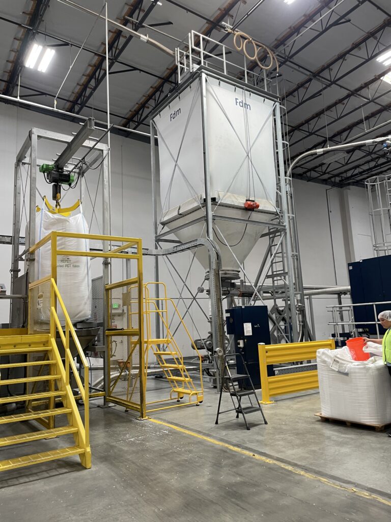 Large funnel feeding shredded plastic into machinery for recycling